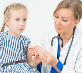 Doctor puts adhesive bandage on child finger.