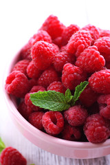 Ripe sweet raspberries in bowl on table close-up