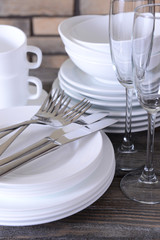 Set of white dishes on table on brick-wall background