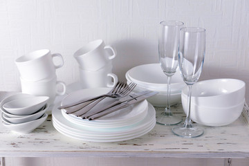 Set of white dishes on table on light background