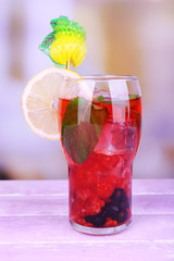 Glasses of cold berry cocktail with lemon on wooden table