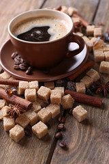 Brown sugar, spices and cup of coffee on wooden background