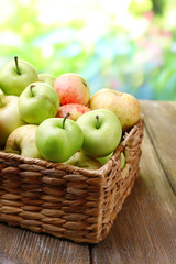 Ripe apples in basket on table on natural background