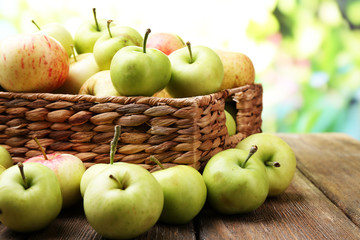 Ripe apples in basket on table on natural background