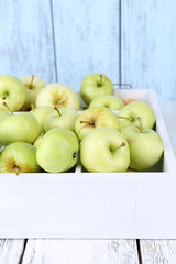 Ripe apples in box on wooden table close-up