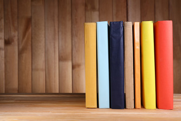 Books on wooden table on wooden wall background