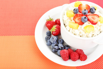 Cottage cheese with fruits and berries in bowl on table