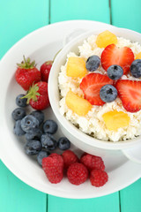 Cottage cheese with fruits and berries in bowl on wooden table