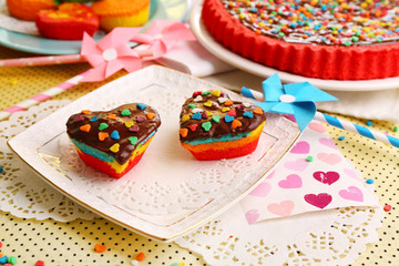 Delicious rainbow cakes on plates, on bright background