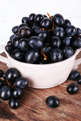 Purple grapes in bowl on wooden background