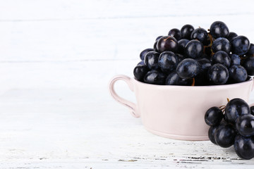 Purple grapes in bowl on wooden background