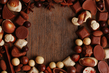 Fototapeta na wymiar Frame of different kinds of chocolates on wooden table close-up