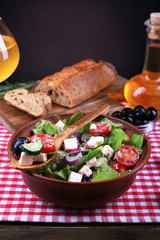 Bowl of Greek salad served with olive oil and glass of wine
