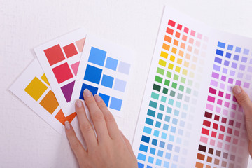 Woman choosing color for wall from swatches in room