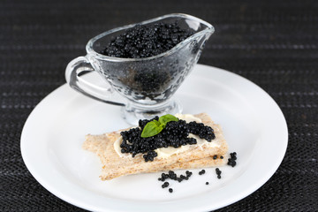 Fototapeta na wymiar Slice of bread with butter and sauceboat with caviar