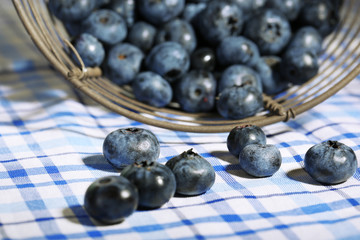 Tasty ripe blueberries in metal basket, on tablecloth