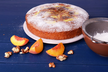 Delicious cake with peach and nuts on wooden table