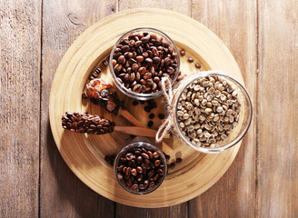 Coffee beans in jars on bamboo plate on wooden background