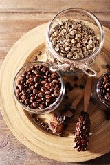 Coffee beans in jars on bamboo plate on wooden background