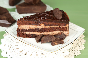 Chocolate cake on plate on color wooden background