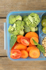 Tasty vegetarian food in plastic box on wooden table
