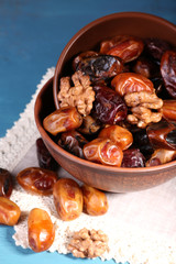 Tasty dates fruits in bowls, on blue wooden background