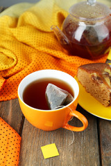 Cup of tea, teapot and tea bags on wooden table close-up