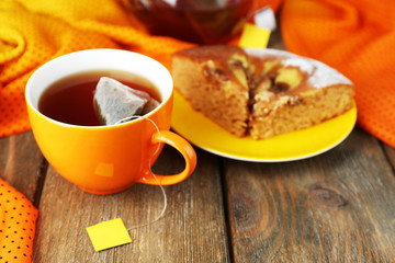 Cup of tea, teapot and tea bags on wooden table close-up