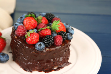 Tasty chocolate cake with different berries, on wooden table