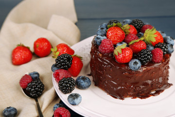 Tasty chocolate cake with different berries, on wooden table