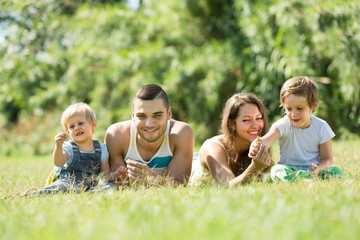 Fototapeta premium Rodzice z dziećmi na trawie