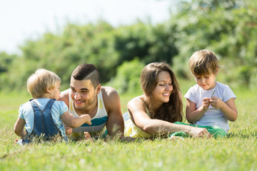 Fototapeta premium Rodzice z dziećmi na trawie