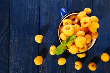 Yellow raspberries in dark blue mug and wildflowers