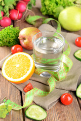 Glass of water with vegetables and measuring tape