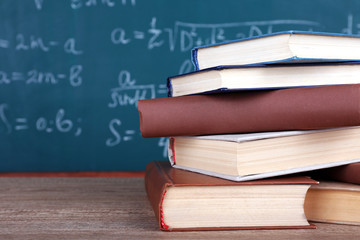 Books on wooden table on blackboard background