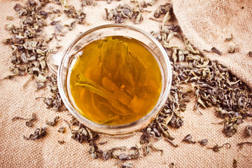 Green tea in transparent glass on linen fabric. 