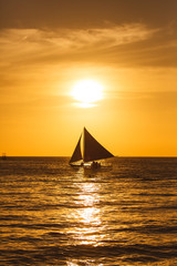 Obraz na płótnie Canvas Sailboat at sunset on a tropical sea. Silhouette photo.