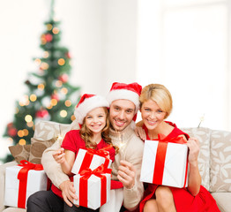 Obraz na płótnie Canvas smiling family holding gift boxes and sparkles