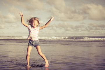 Obraz premium little girl jumping on the beach at blue sea shore in summer va