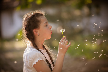 Girl blowing on white dandelion