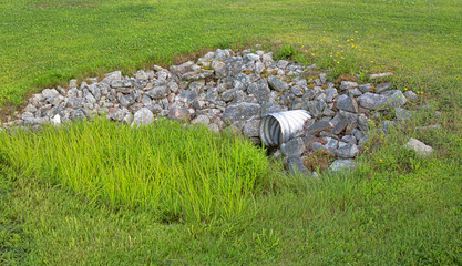 Storm culvert surrounded by rocks and grass - obrazy, fototapety, plakaty