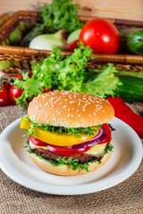 homemade hamburger with fresh vegetables on cutting board