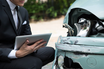 Insurance Agent Examining Car After Accident