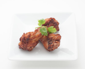 Fried chicken legs with celery leaves on white plate