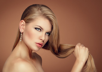 Naklejka premium Cute model holding her long hair wearing brilliant earrings