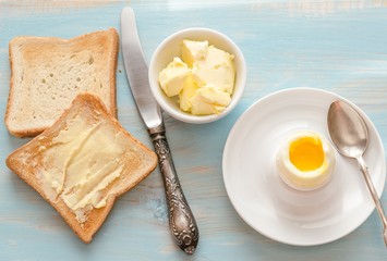 Boiled egg with crispy toasts on the wooden table