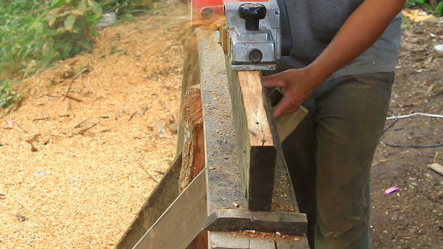 carpenter worker's power tool while planing a piece of wood 	