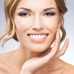 Fototapeta premium Woman touching skin or applying cream, on grey