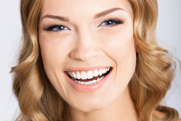 Young cheerful smiling woman, on gray