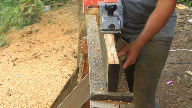 carpenter worker's power tool while planing a piece of wood 	